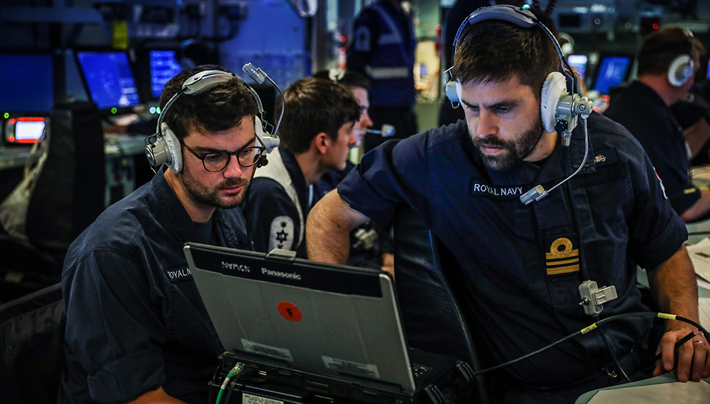 two brown haired and bearded blue uniformed crewmembers, on a lieutenant commander on Operations Room of vessel