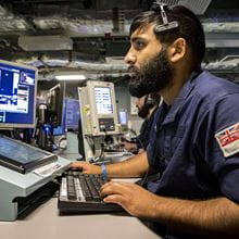 blue uniformed brown haired and bearded weapon specialist tracking a radar screen