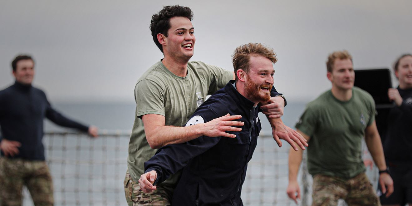 crewmates on board dressed in civilian clothing on downtime enjoy recreation on deck playing bucket ball