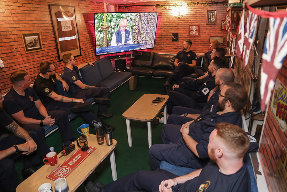 dressed in blue uniforms the crew of HMS Queen Elizabeth aircraft carrier watch the funeral of HM Queen Elizabeth II funeral live in their mess deck