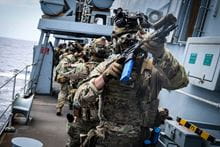 A Royal Marine on the deck of a ship holding a gun