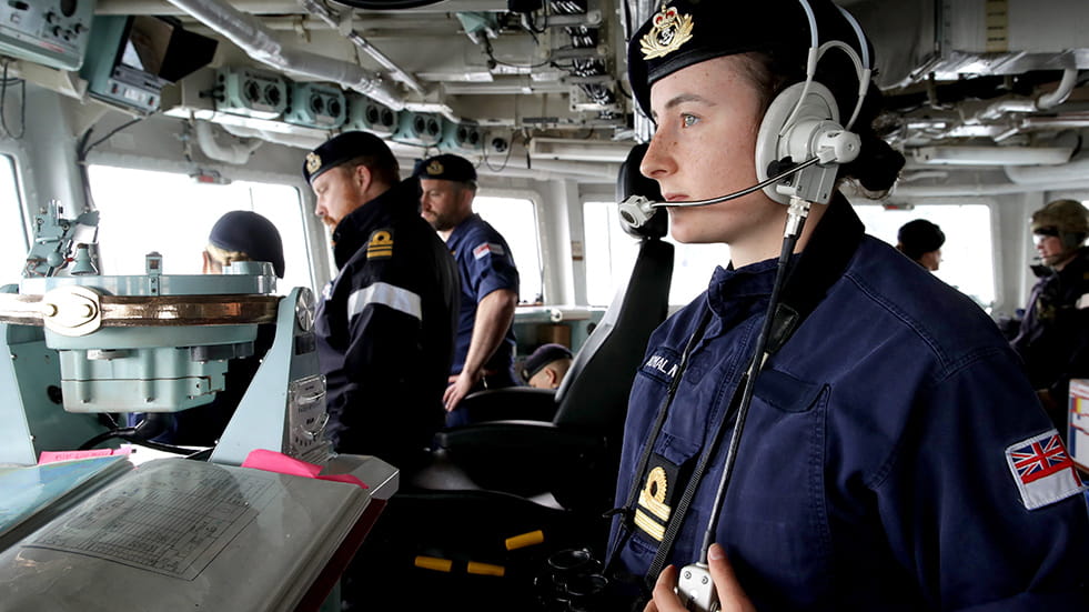 Officer on the bridge of a ship looking out to sea