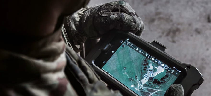 Over the shoulder image of a Royal Marine holding a computer screen, with a map showing on the screen.