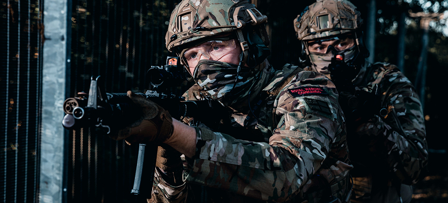 Two Royal Marines with one holding a gun pointing at someone off camera.