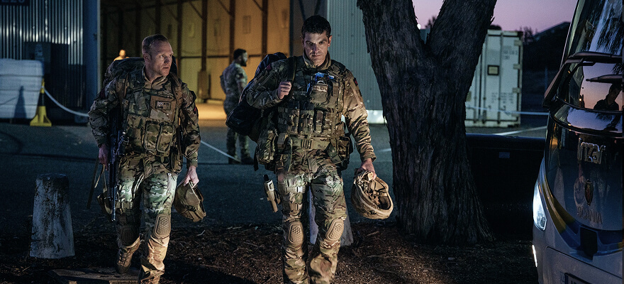 Two marine commandos walking together, holding their helmets and other equipment.