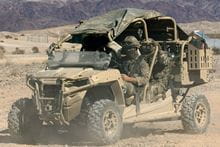 Two Royal Marines sitting in a vehicle in the desert.
