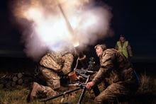 Three Royal Marines firing a rocket mortar in the night time.