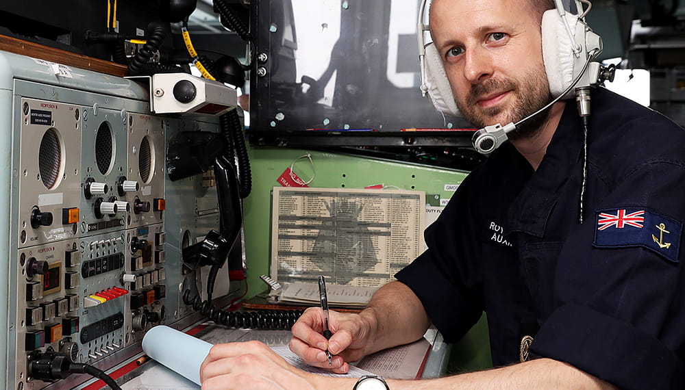 RFA Apprentice communicator specialist smiles towards camera whilst writing. Exercise medical endeavour.