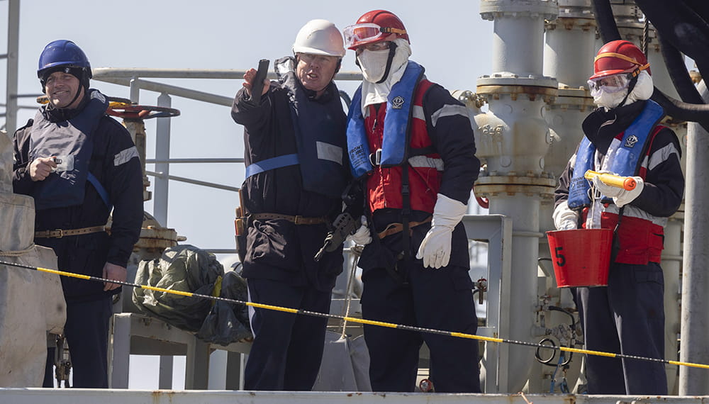 RFA Tidespring's personnel prepare to conduct a replenishment at sea. Personnel working, one points forward whilst the other listens another smiles. 