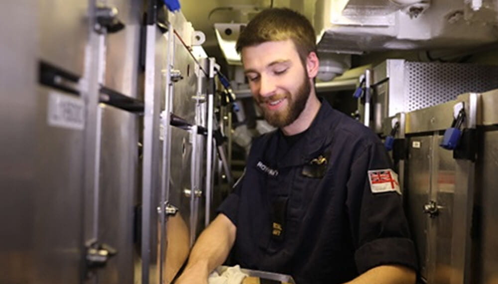 Submariner smiling, while working on a submarine