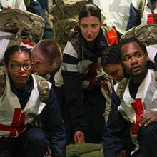 Multiple medical personnel stretchering a person through a corridor
