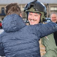 Navy personnel hugging someone, meeting them off of Carrier Strike Group