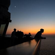 Silhouetted crew at sunset aboard HMS Prince of Wales.