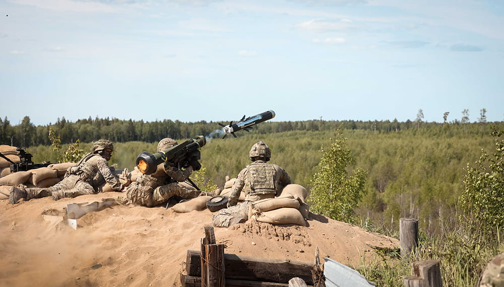Commando firing a Javelin surrounded by sand bags