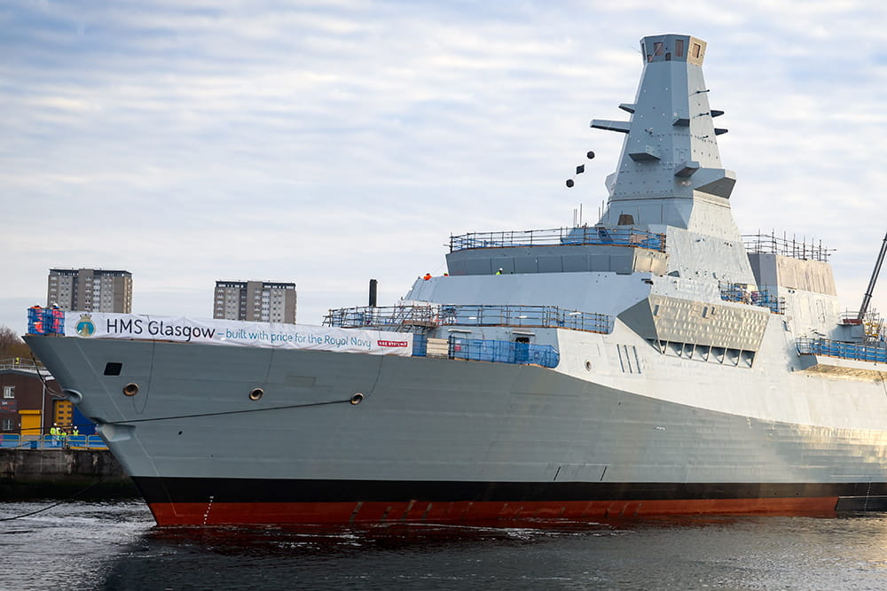 HMS Glasgow being towed an maneuvered by smaller tugboats