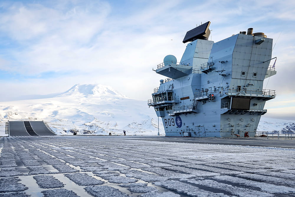 Royal-Navy-Equipment-Queen-Elizabeth-Class-03-always-ready.jpg Icey deck of an aircraft carrier with a snow-covered mountain in the distance