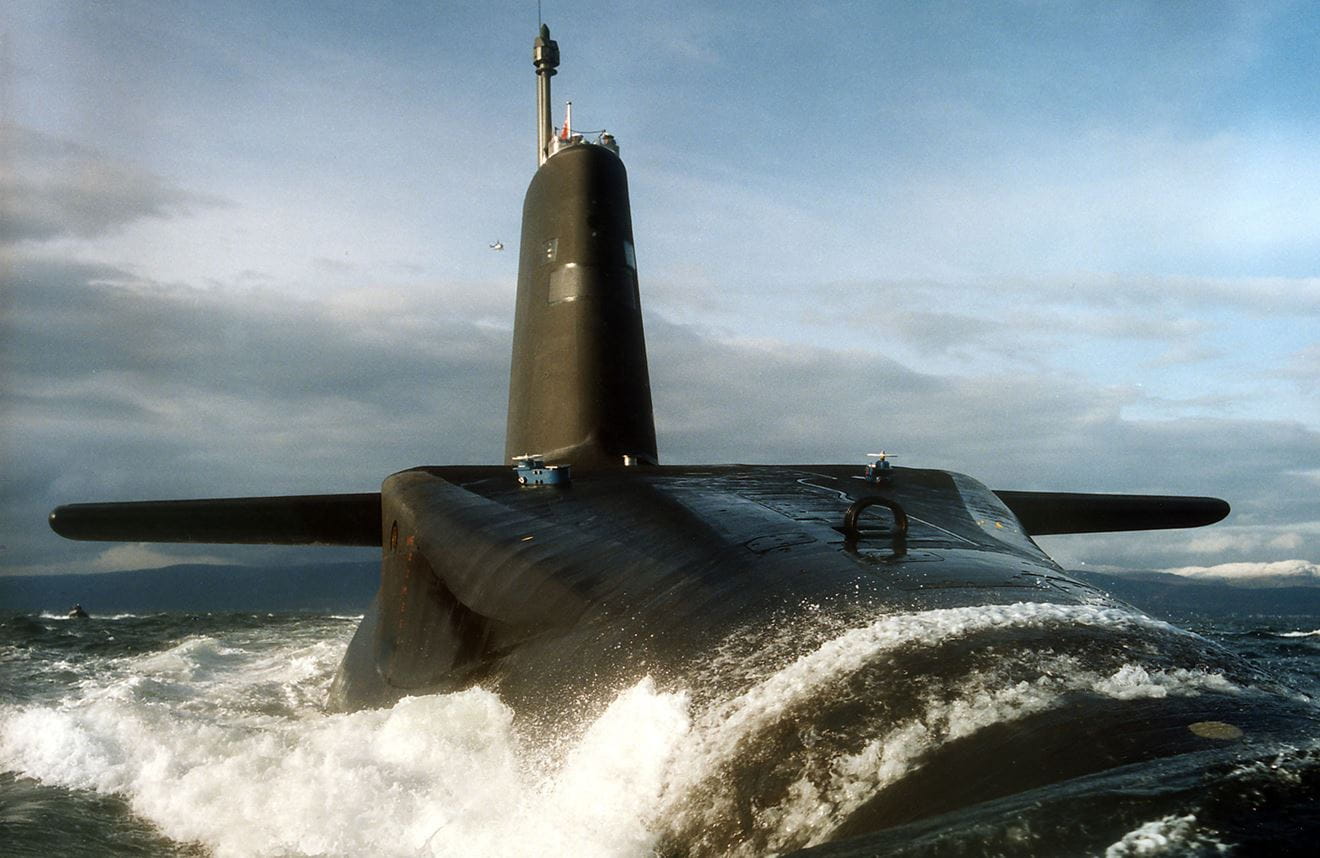 Massive Trident submarine surfaces with water pouring over its surface