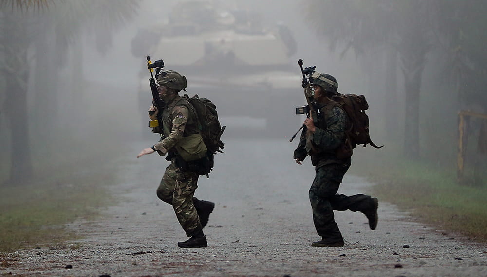 Royal Marines cross road in front of a tank