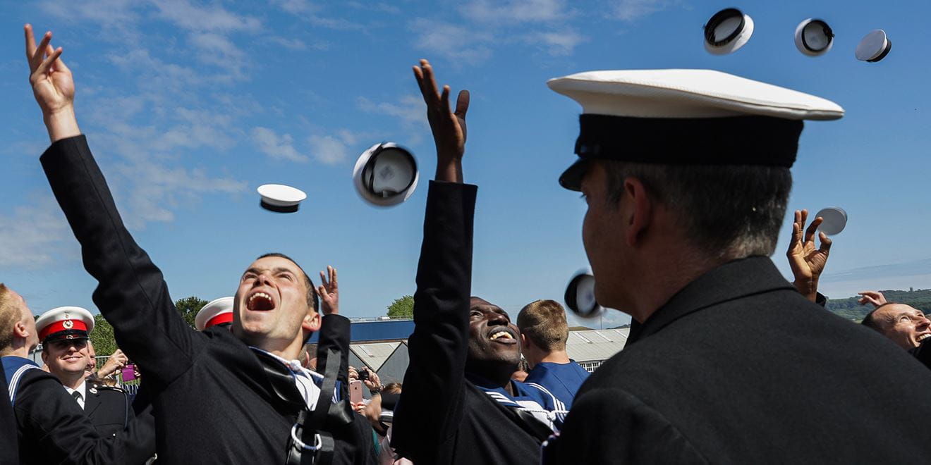 Royal-Navy-Bases-and-Stations-HMS Raleigh-02-base Trainee sailors celebrating at passing out parade throwing their hats in the air
