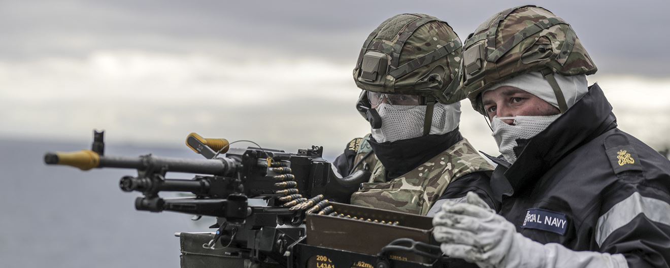 Two Royal Navy sailors firing a heavy machine gun