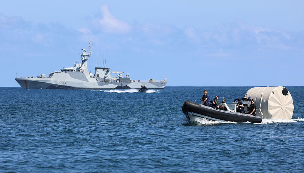 Royal-Navy-Global-Operations-07-Indo-Pacific HMS Spey in background delivers humanitarian aid via small inflatable vessel in forground