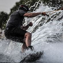 An individual in a black swim suit wake boarding on the sea
