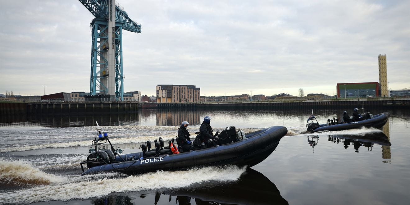 2 police rib boats race through the port at speed