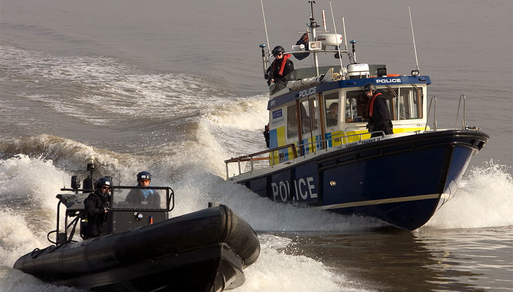 A police rib boat heads towards the camera with a police harbour patrol boat at its port side