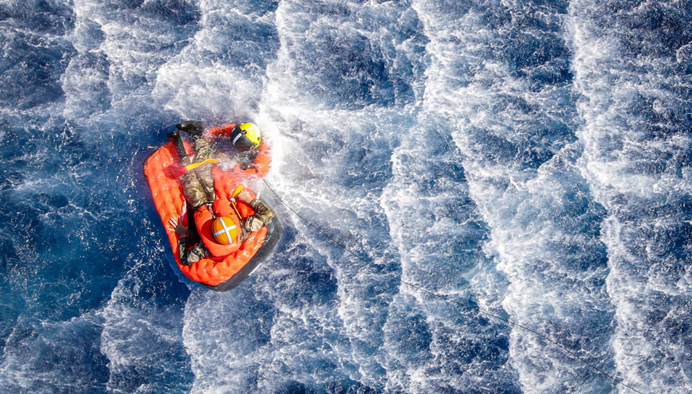 Emergency rescue personnel rescues an individual on a orange inflatable buoyancy aid