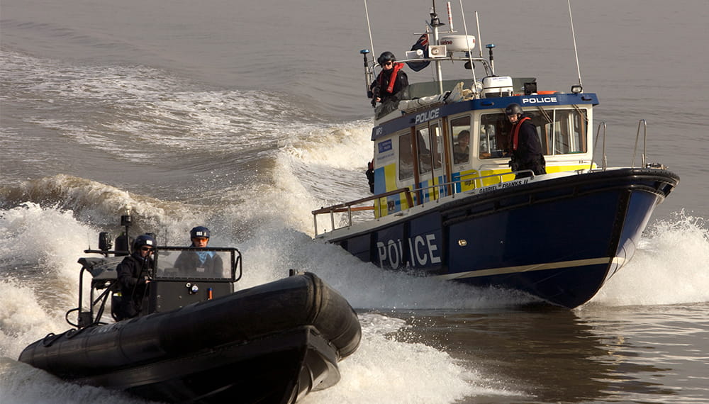A black rib boat and a harbour patrol boat maneuver towards the camera 