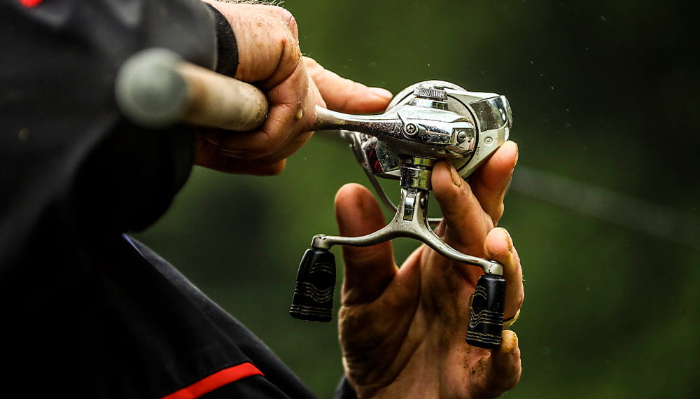 An individual with a fishing rod in their hands adjusts the line