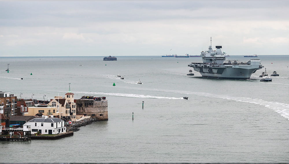 A context image of Portsmouth harbor and a aircraft carrier in the background