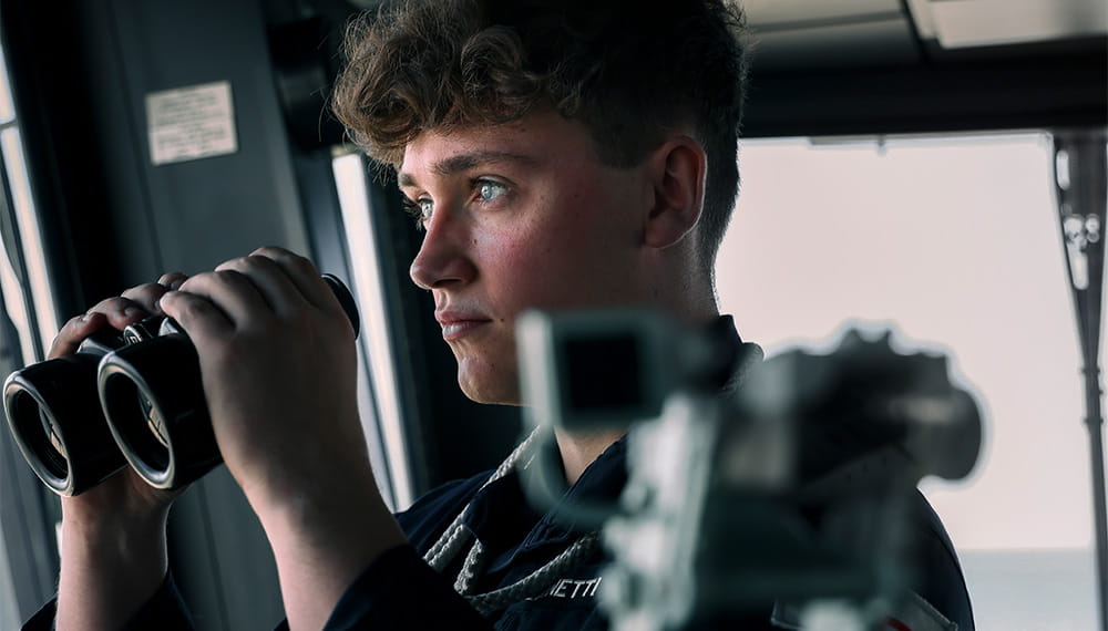 Closeup of a Navy sailor about to glance through binoculars