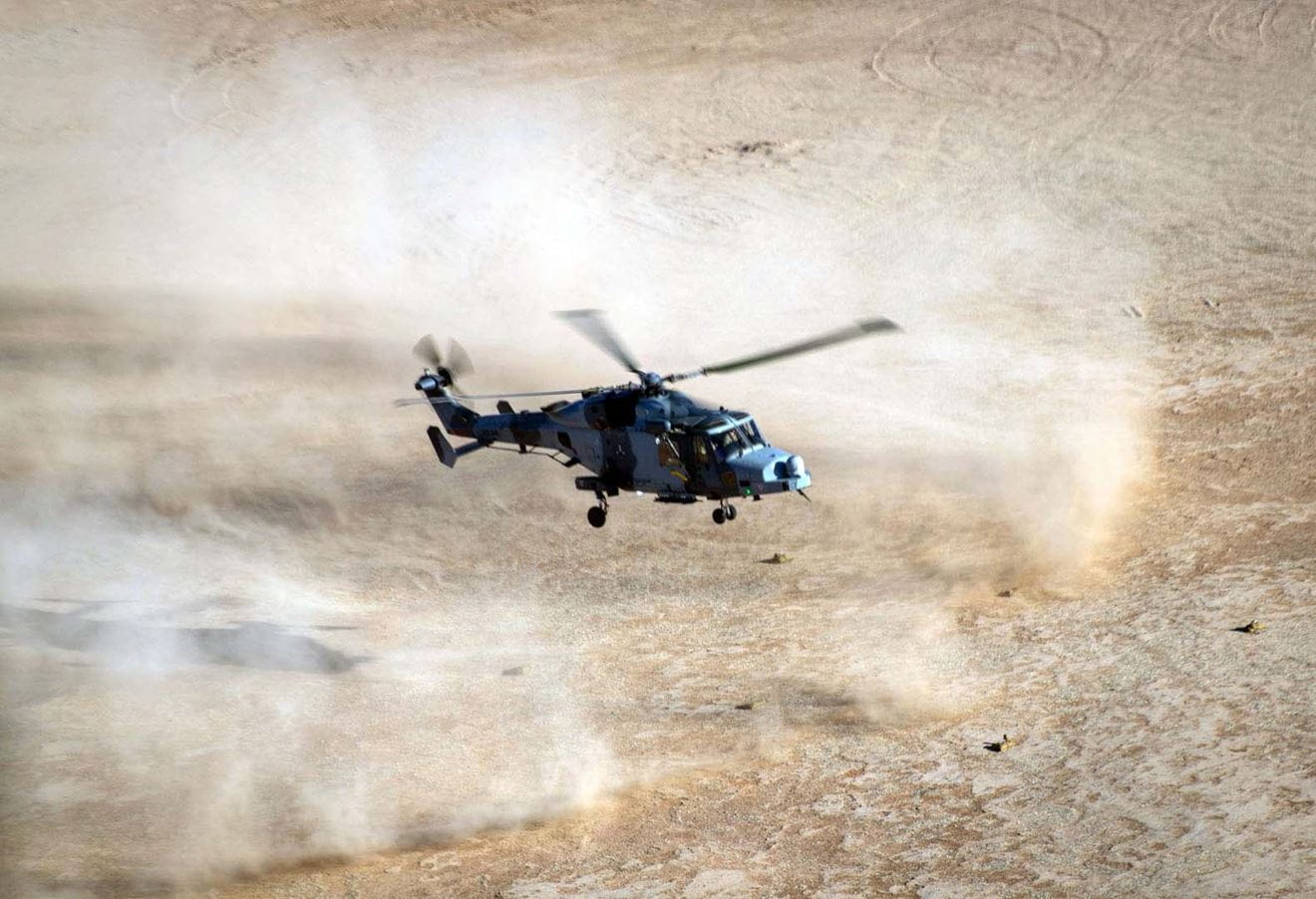 An 847 NAS Wildcat throws up sand and dust as it comes into land