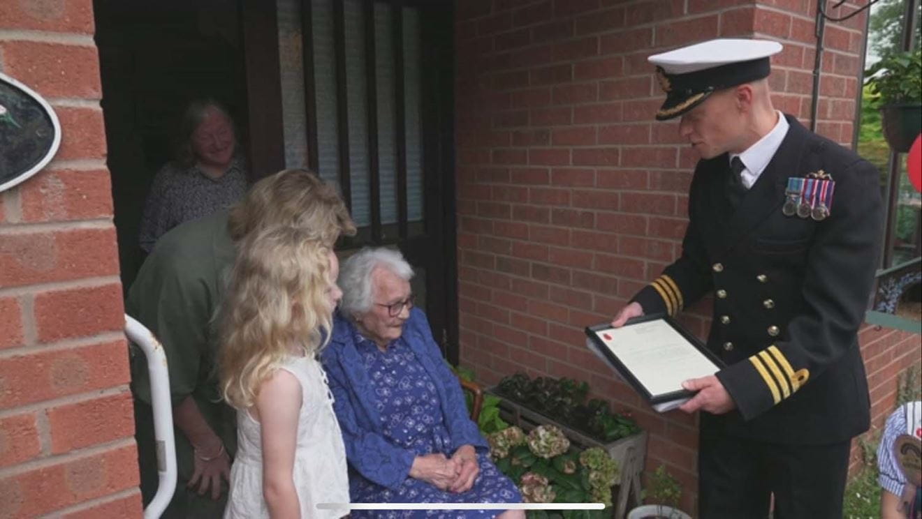 Commander Jonathan Richards presents Thelma Redman with her letter from the First Sea Lord General Sir Gwyn Jenkins RM