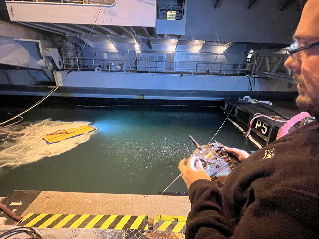 The hull cleaning drone operator manoeuvres it into position to inspect Charles de Gaulles hull