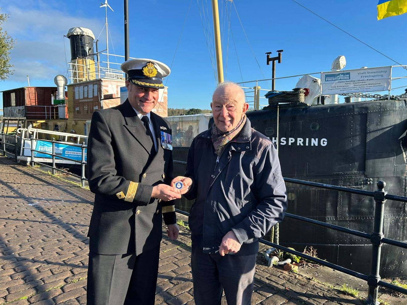 Cdre Shattock presents a challenge coin as a thankyou for Freshsprings hospitality