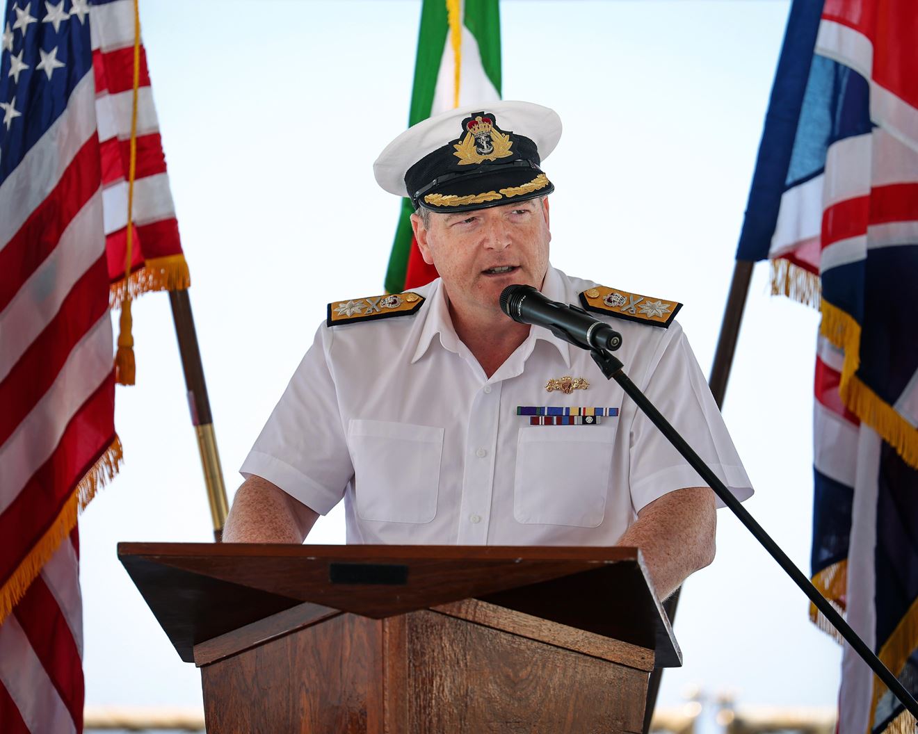 Flanked by the US and UK flags, new SNMG2 Commander Cdre Paul Stroude address guests at the handover ceremony Flanked by the US and UK flags, new SNMG2 Commander Cdre Paul Stroude address guests at the handover ceremony