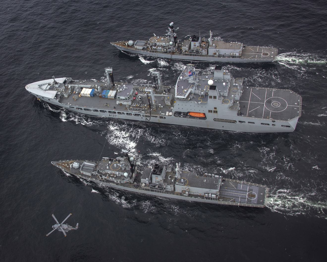 RFA Tiderace conducts a double replenishment at sea with HMS Lancaster (bottom) and Westminster (top) as a Canadian Sikorsky helicopter flies past RFA Tiderace conducts a double replenishment at sea with HMS Lancaster (bottom) and Westminster (top) as a Canadian Sikorsky helicopter flies past