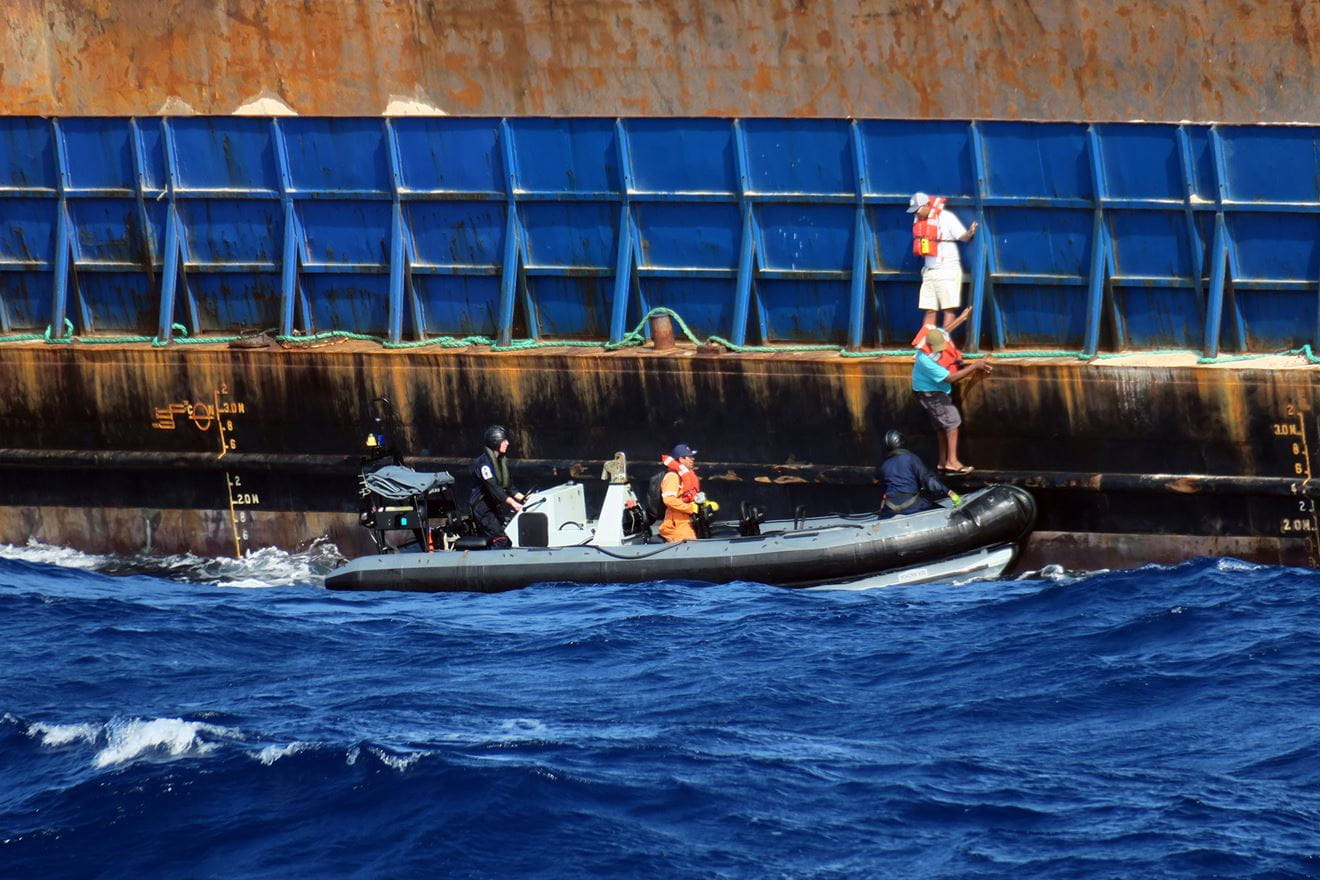 The tug crew step off the barge on to HMS Medway's sea boat