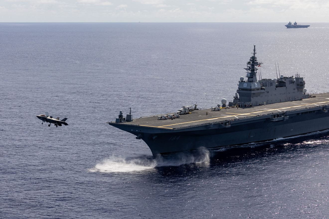A UK F35B Lightning jet launches from Japanese flagship JS Kaga with HMS Prince of Wales in the distance