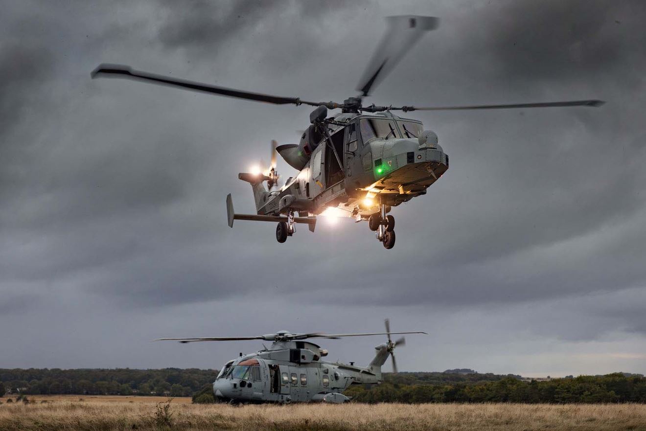 A Commando Wildcat lands at dusk with a Merlin already on the ground