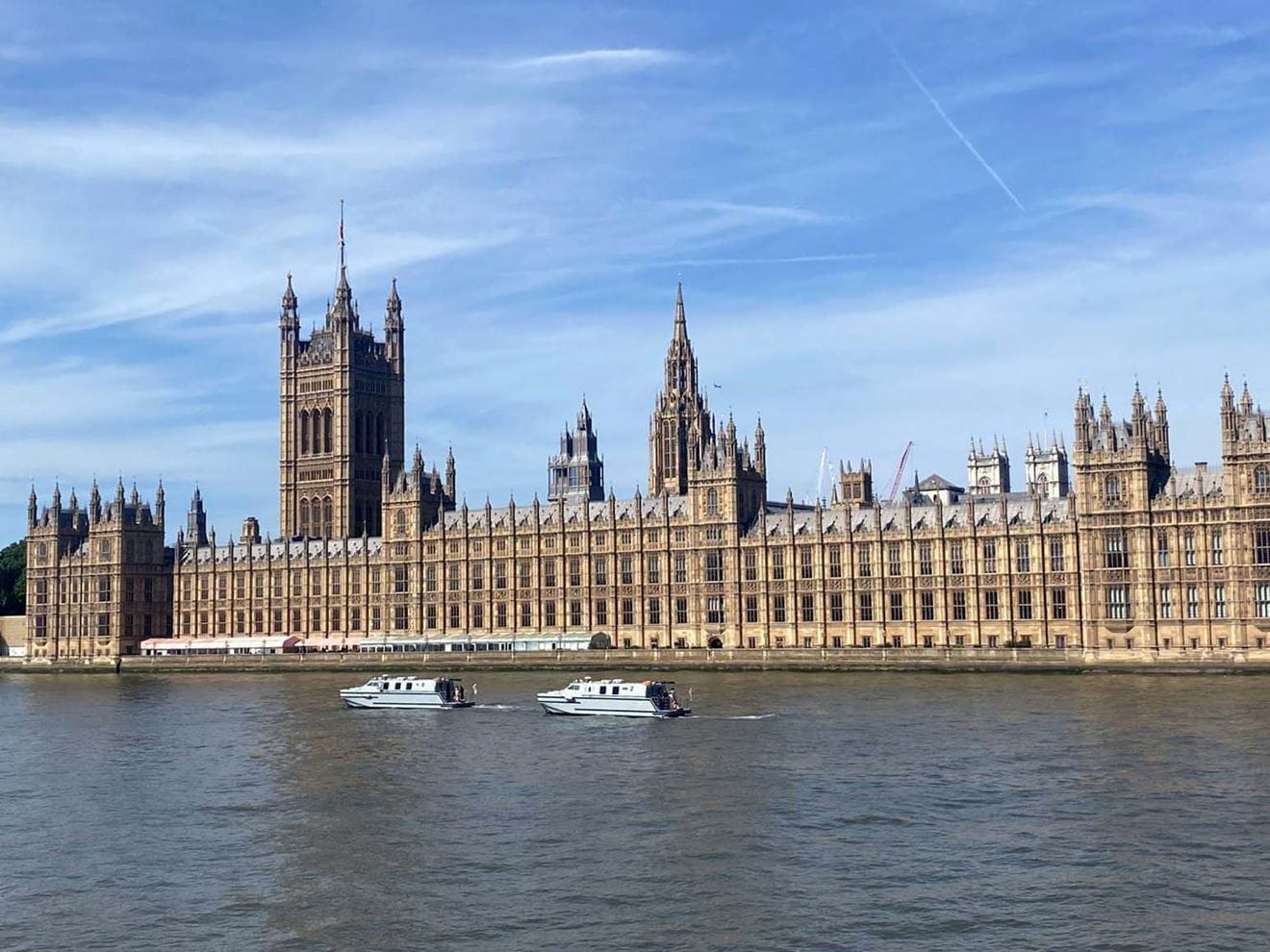 The two training vessels sail past the imposing waterfront facade of the Palace of Westminster
