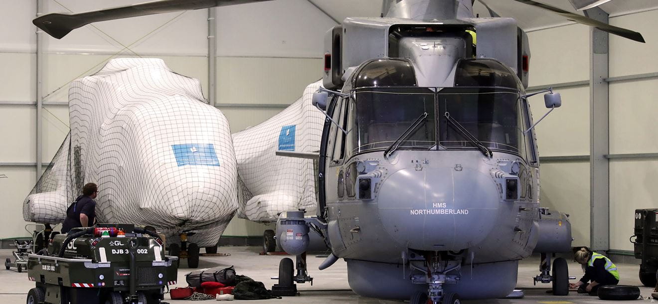 AIR ENGINEER TECHNICIANS WORKING INSIDE A HANGER IN CATANIA ON A MERLIN READY FOR FLYING IN THE MORNING