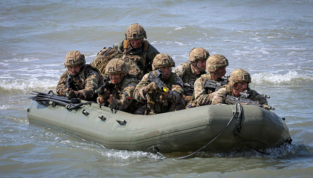 Several Royal Marine commandos with guns in a small green inflatable raiding craft