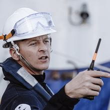 Royal-Navy-Our-People-Our-Values-15-reliability.jpg Sailor wearing a white hard hat and carrying a walkie talkie points