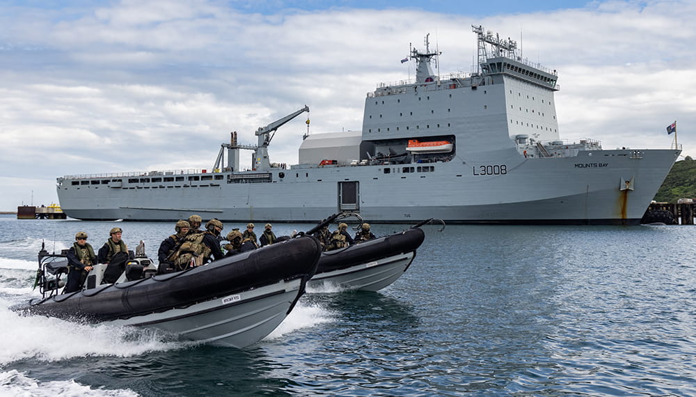 Two Royal Navy ribs speed past RFA Mounts Bay