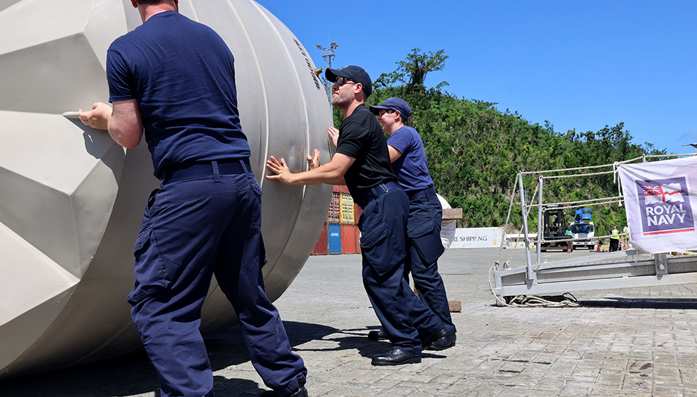 Royal-Navy-What-we-do-Respond-05-providing-aid.jpg Three Royal Navy sailors role a huge humanitarian aid water tank along the ground