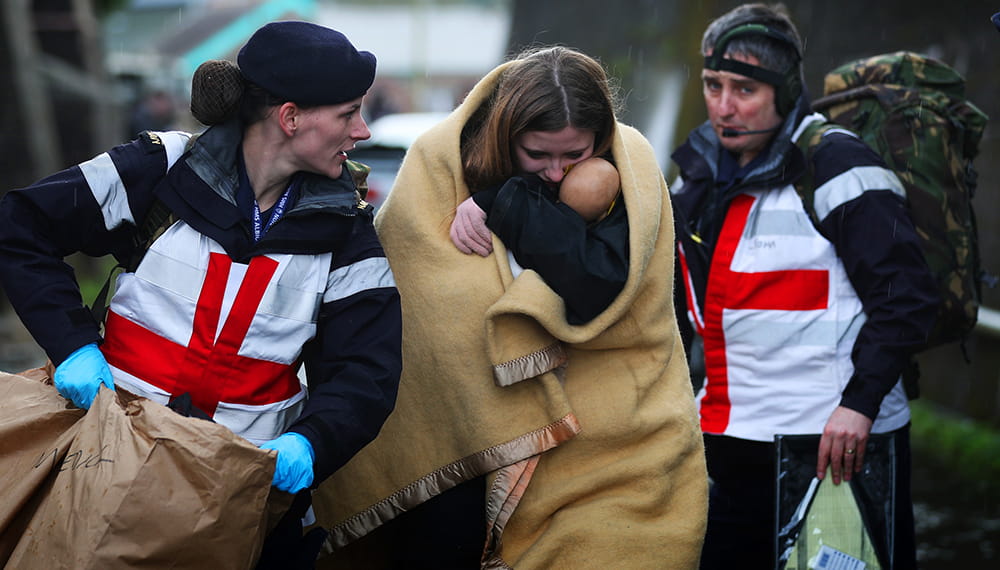 Royal-Navy-What-we-do-Respond-06-getting-people-to-safety.jpg Two Royal Navy medics support lady and a baby wrapped in a blanket