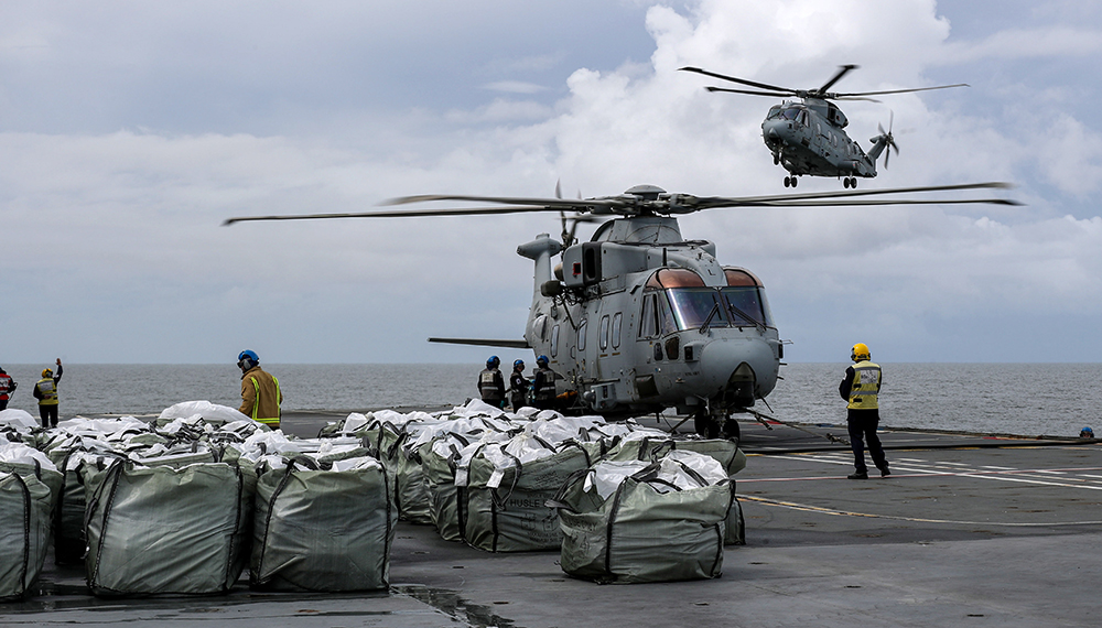 Royal-Navy-What-we-do-Respond-07-preparing.jpg Merlin helicopter aboard the deck of an aircraft carrier surrounded by humanitarian aid supplies